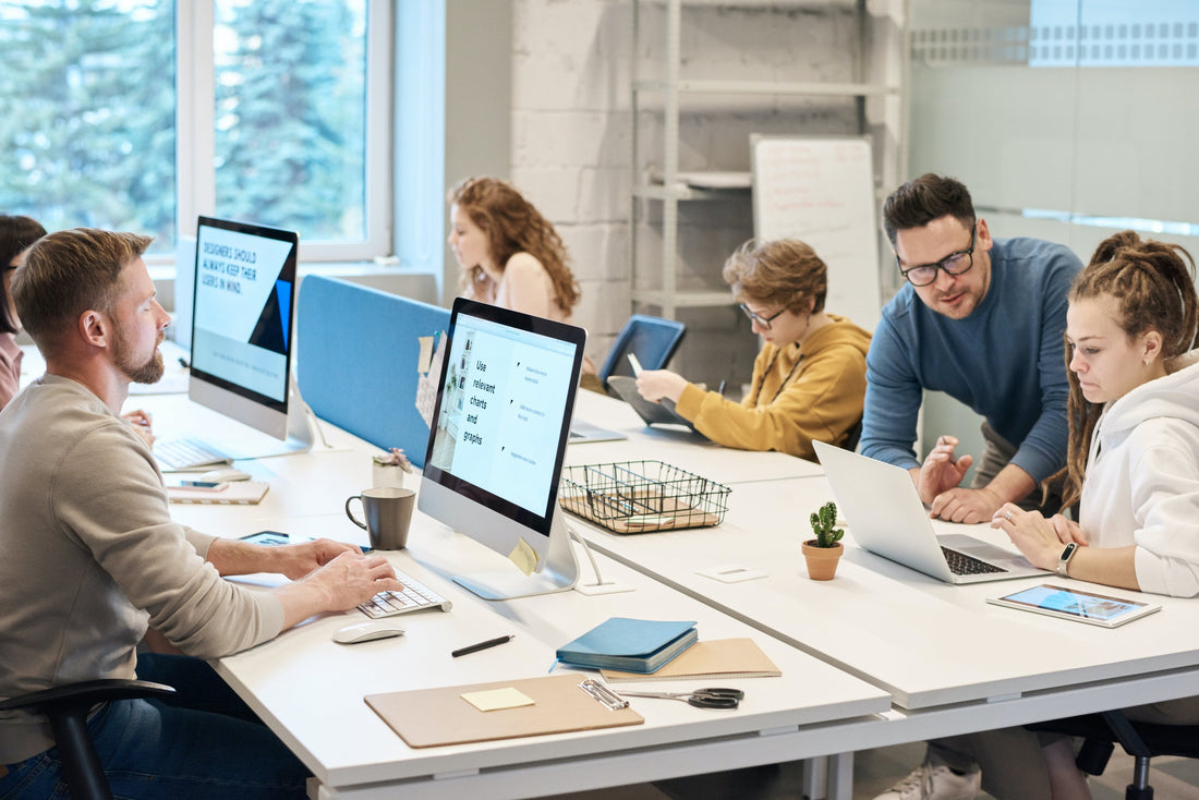 A people sitting at a desk with a computers, looking focused and determined. 