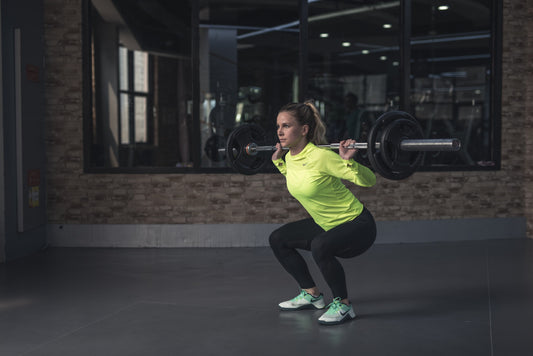 A person lifting weights while in a squat position. The individual maintains a straight back, knees aligned with toes, and hips pushed back. The lift is executed with proper form, promoting muscle engagement and safety.