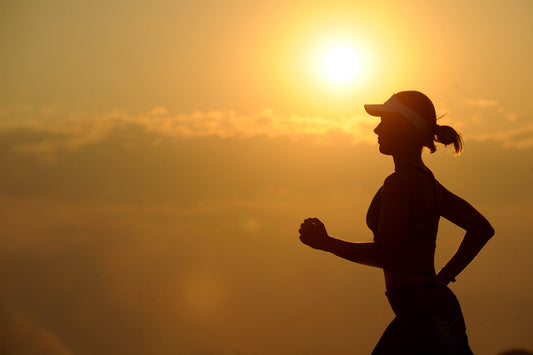 Image of a woman joyfully running outdoors with the vibrant sunrise in the background, symbolizing the empowering connection between exercise, positivity, and the beauty of embracing one's body